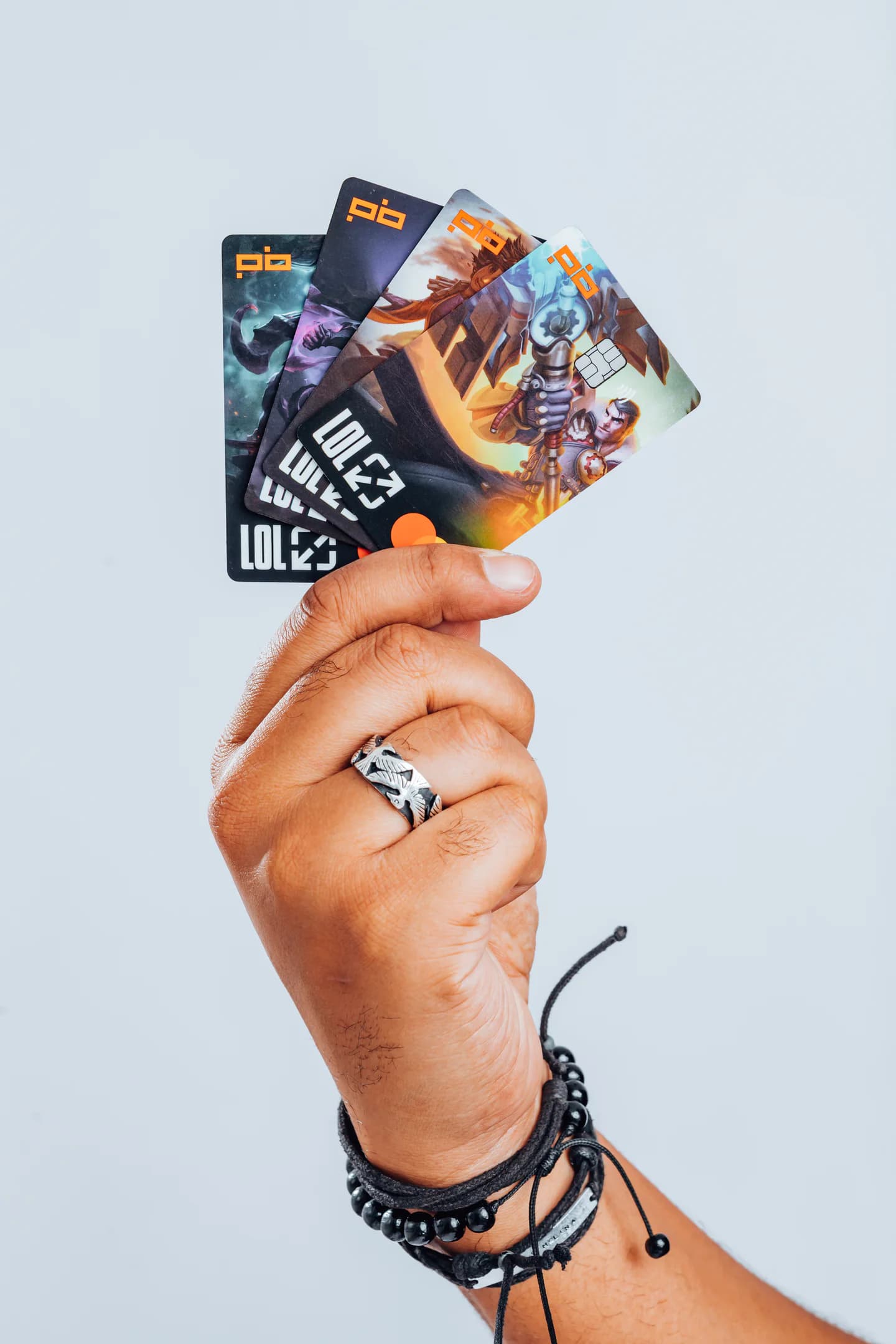 Mão segurando os cartões do Players Bank com artes de League of Legends.