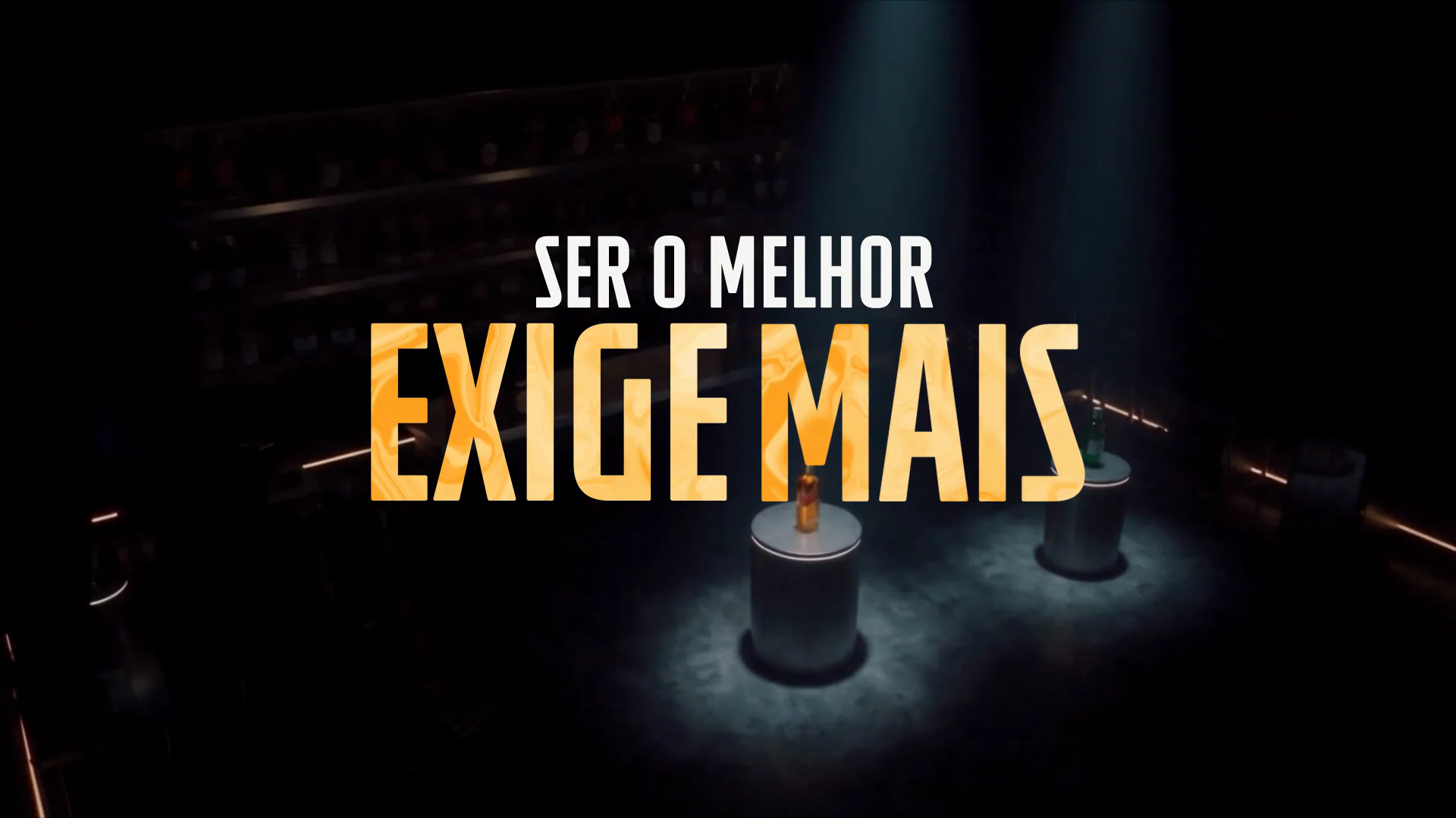 Quadro do filme: a frase "Ser o melhor exige mais" em letras douradas sobre um estúdio escuro com duas garrafas iluminadas.