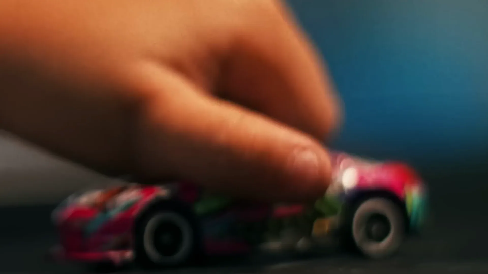 Quadro do filme: um dedo empurra um carrinho de brinquedo com a pintura do carro de drift.