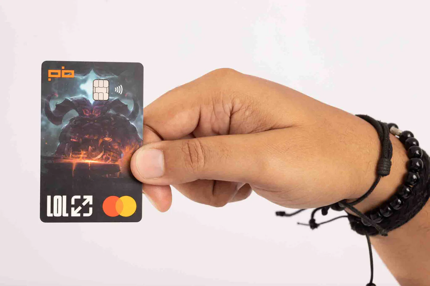 Mão segura um Cartão LoL do Players Bank sobre fundo claro.