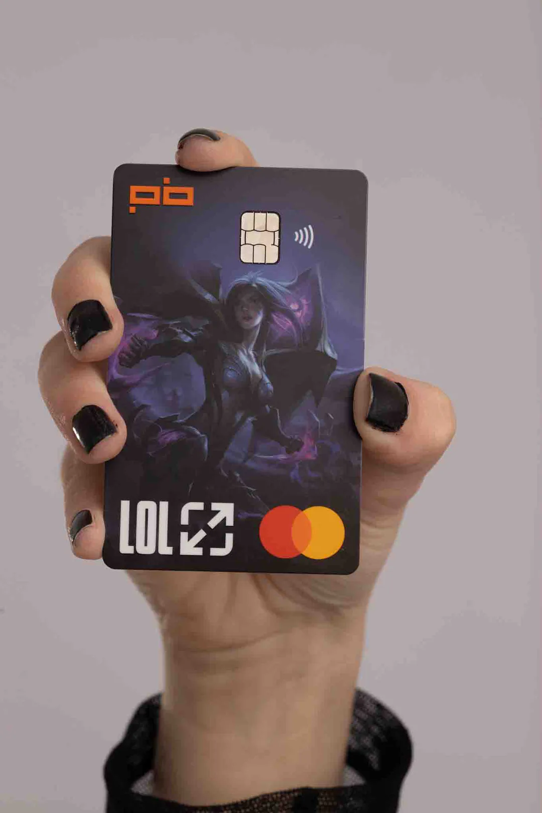 Mão de unhas pretas segura um Cartão LoL do Players Bank de arte escura.