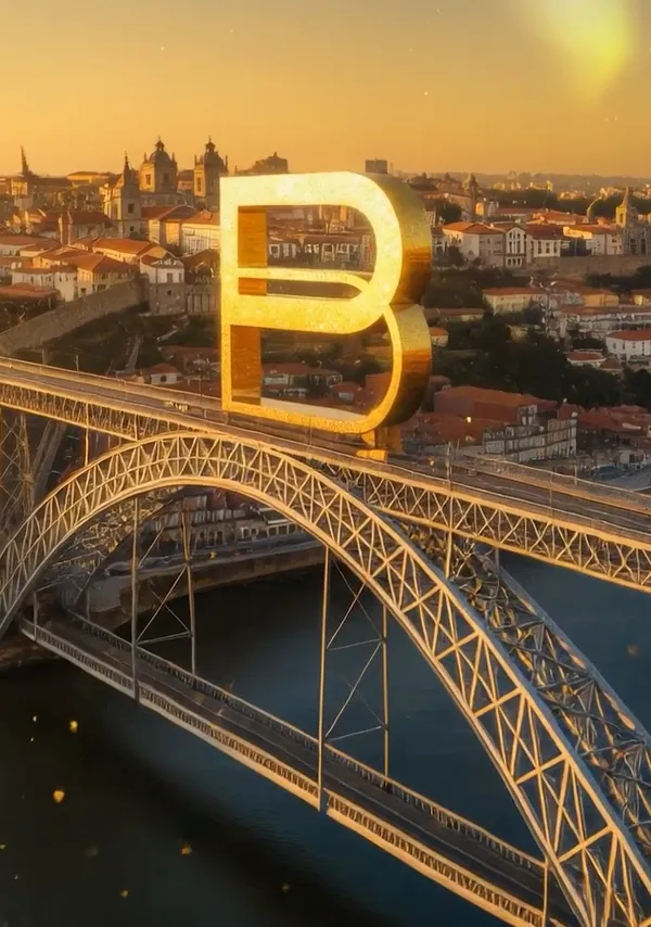 A letra B dourada sobre uma ponte de ferro no Porto, ao pôr do sol.