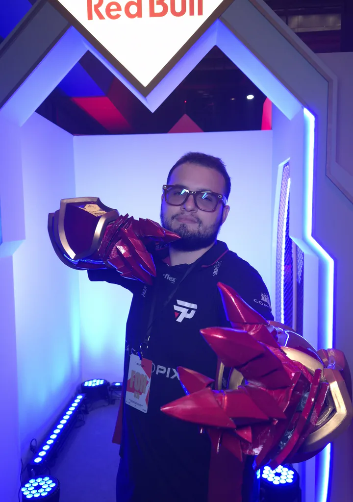 Marco Guimarães, da BePlus, com as manoplas da Shyvana na cabine do estande, no quinto dia do torneio.