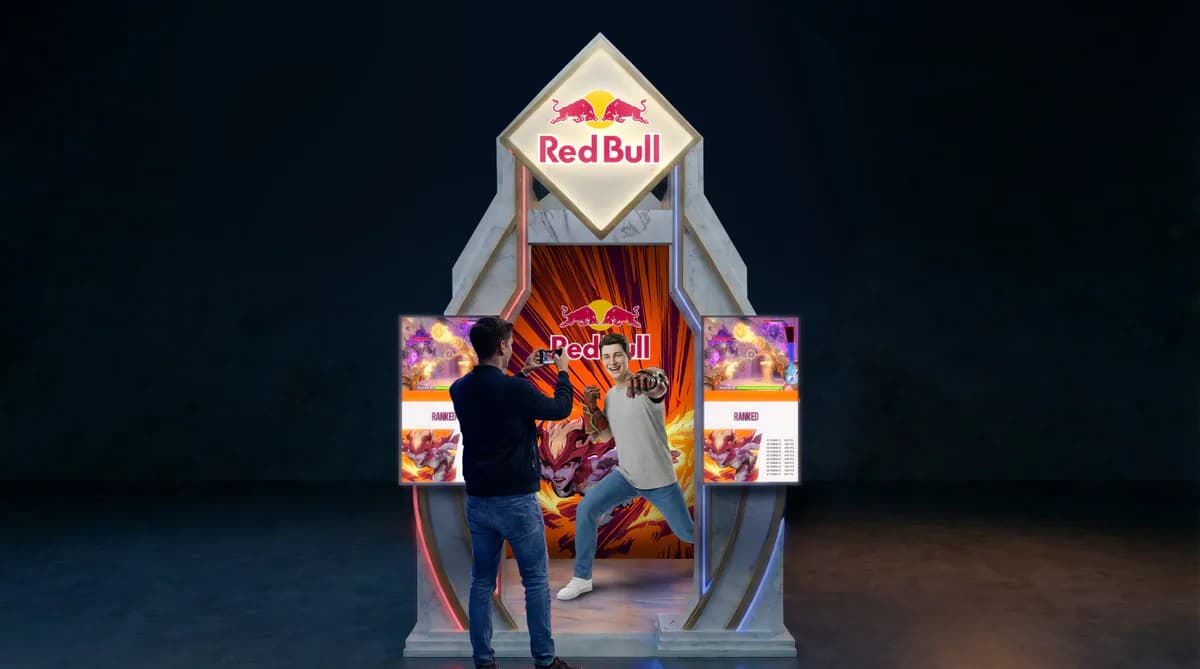 Render da frente do estande: o portal com o logo da Red Bull, duas telas laterais e uma pessoa posando para foto.