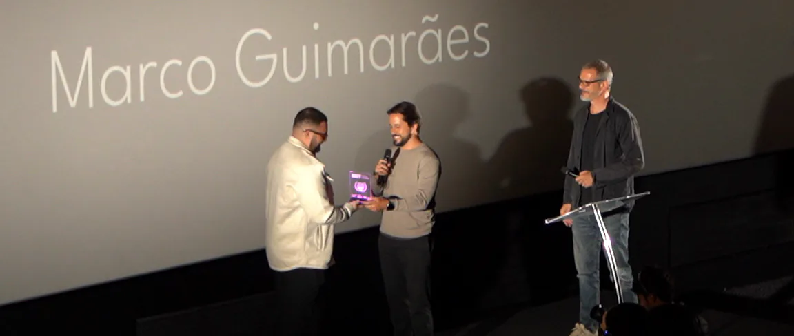O Marco recebe o troféu no palco, sob o telão com Red Bull ClassiCS 2025, abertura cinemática, Marco Guimarães.